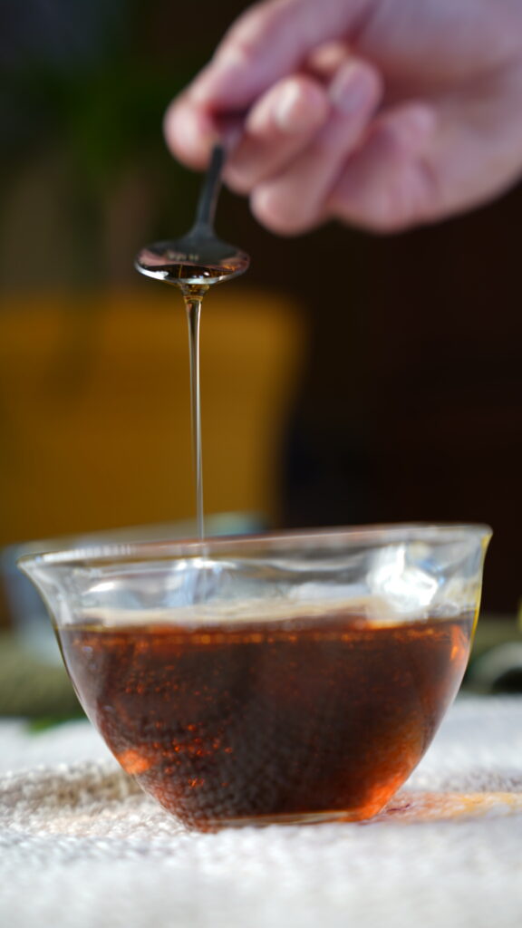 Bowl of maple syrup being mixed around with a medal spoon
