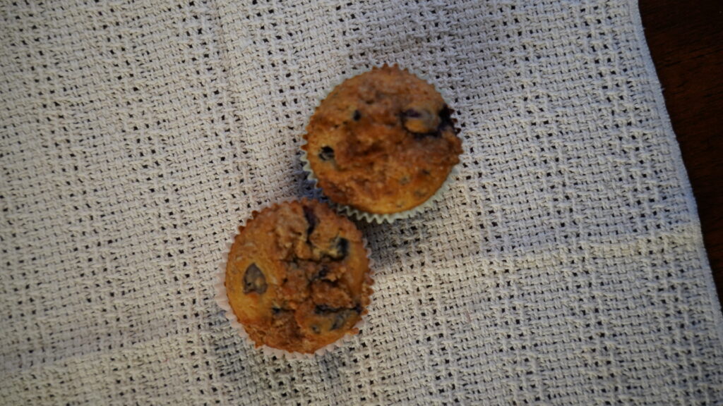Two blueberry muffins with a cinnamon crumble on a white towel