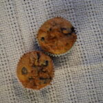 Two blueberry muffins with cinnamon crumble on a white towel