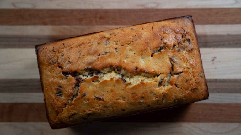 Close-up image of cranberry nut bread on a striped cutting board